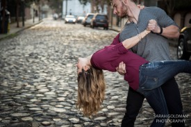engaged couple dips on a cobblestone street in charleston
